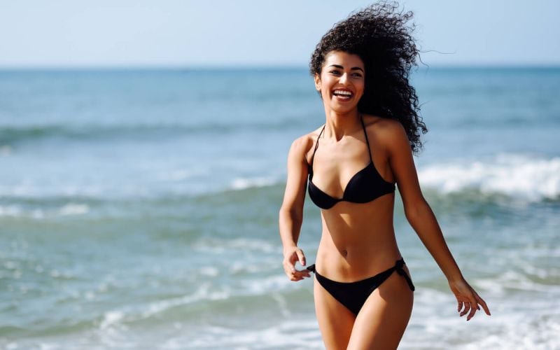 happy woman on beach after laser hair removal