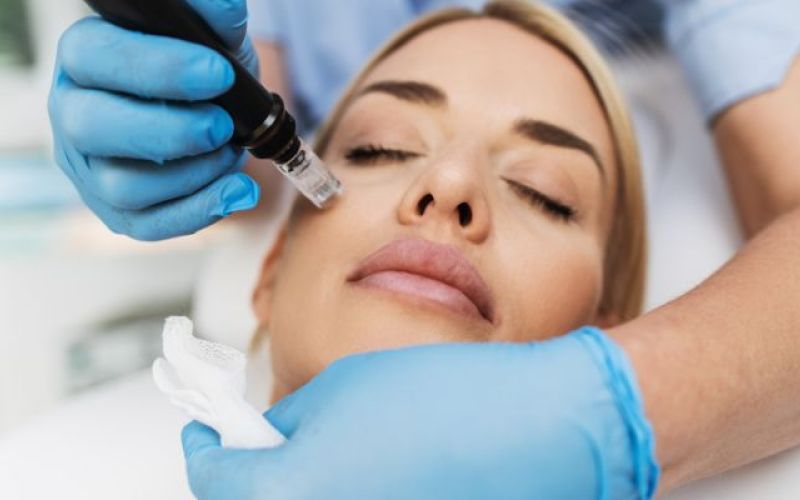 Woman laying down while medical professional uses skincare tools on her face
